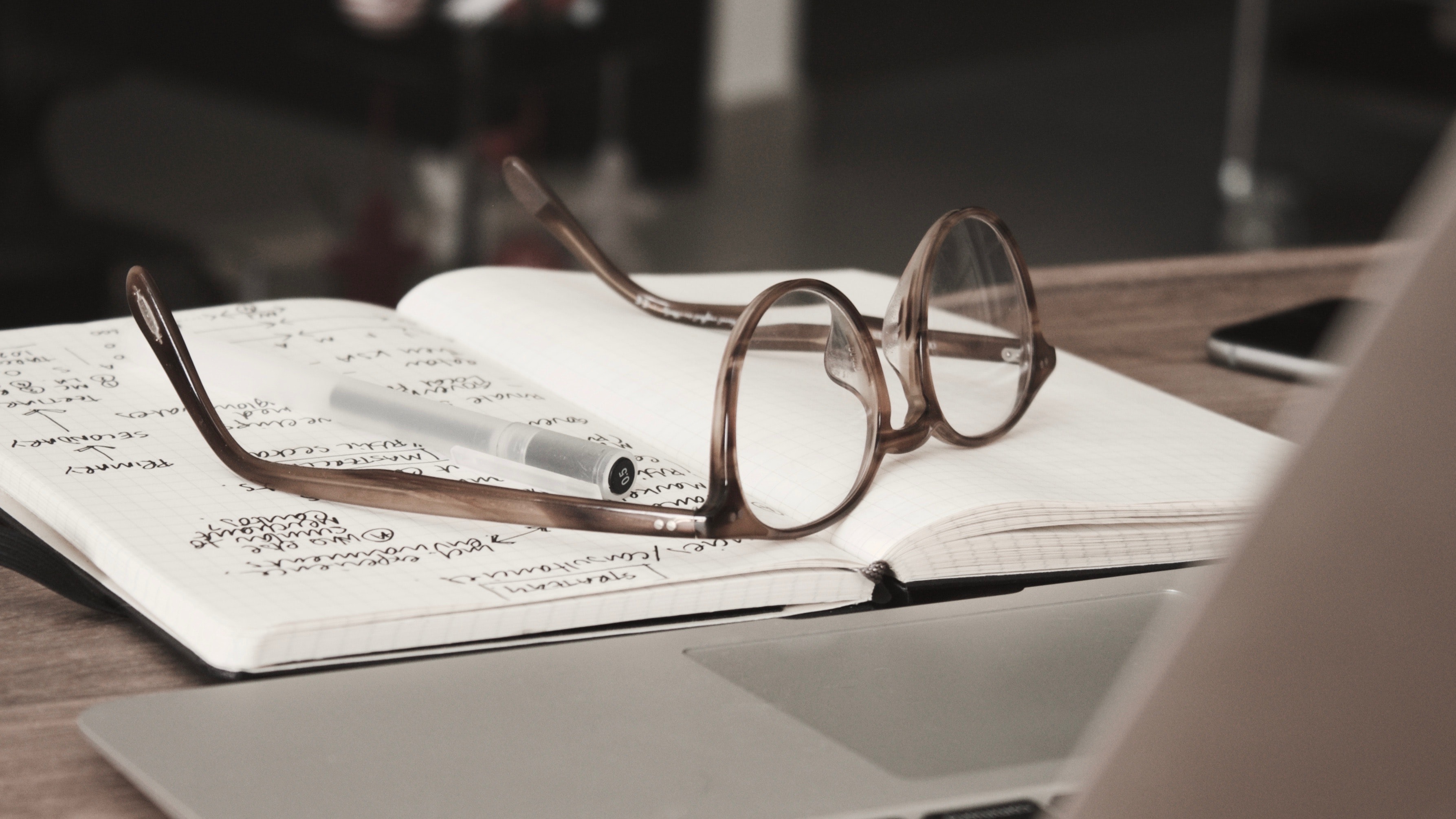 Glasses on a notebook with a pen