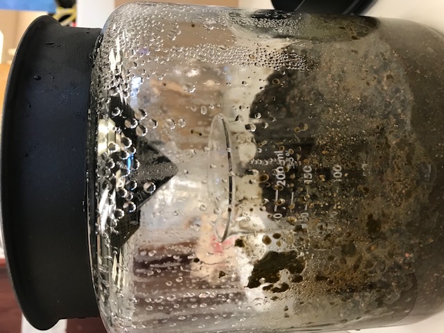 A jar containing long pepper at the bottom with a beaker in the middle and a cone of ice attached to the top. There is condensation on the jar. 