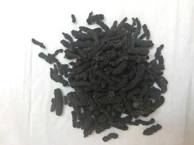 Large long black kernels of pepper with small bumps on them. 