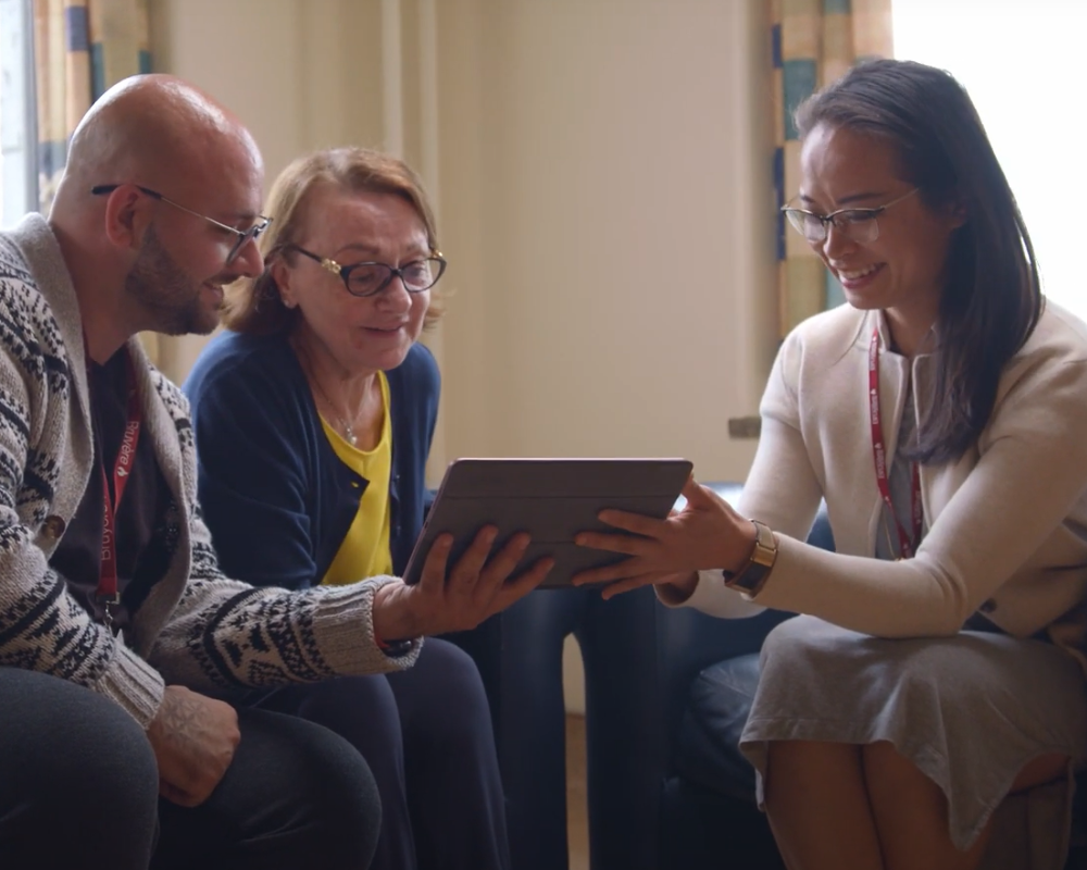 Dr. Amy Hsu smiling and showing information on an iPad to a woman and her adult son.