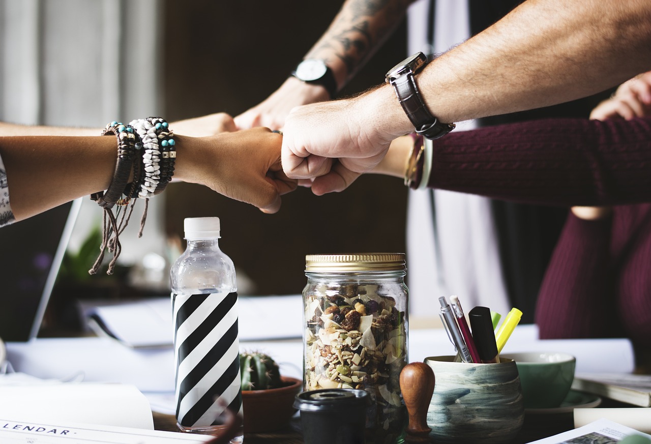 Group of people fist bumping over their paperwork.