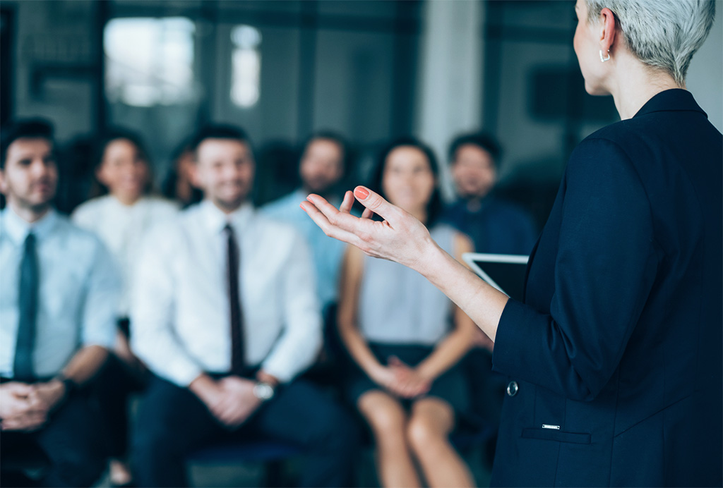 A woman speaking in front of a group.