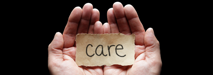 The word "care" on a piece of brown paper, in a palm