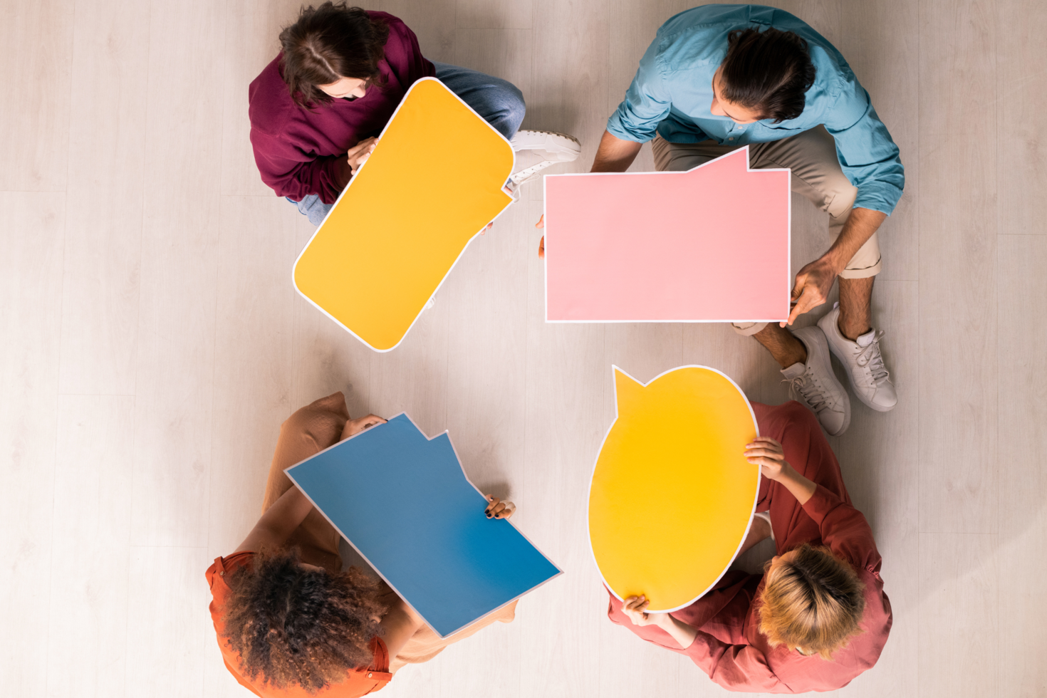 Picture of people holding yellow, pink and blue speech bubbles
