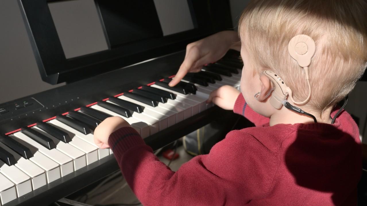 Boy with cochlear implants learning piano