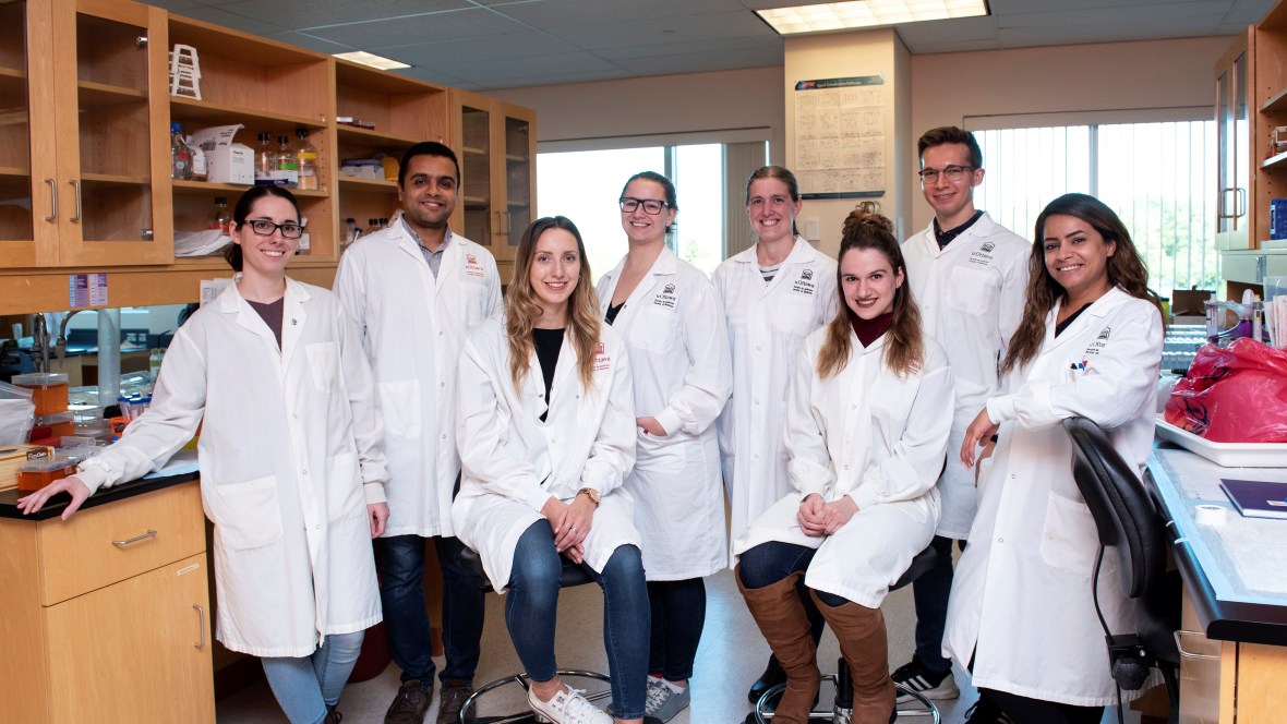 A group of uOBMRI trainees standing and smiling together in their lab.