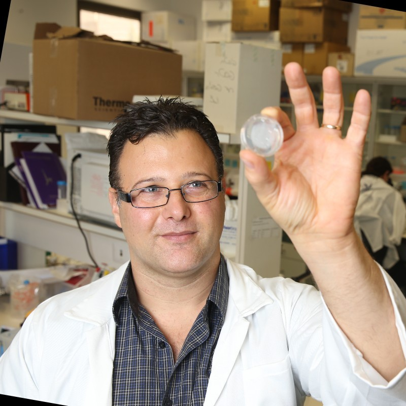 Picture of Dr.Einav Gross holding up a circular object. 