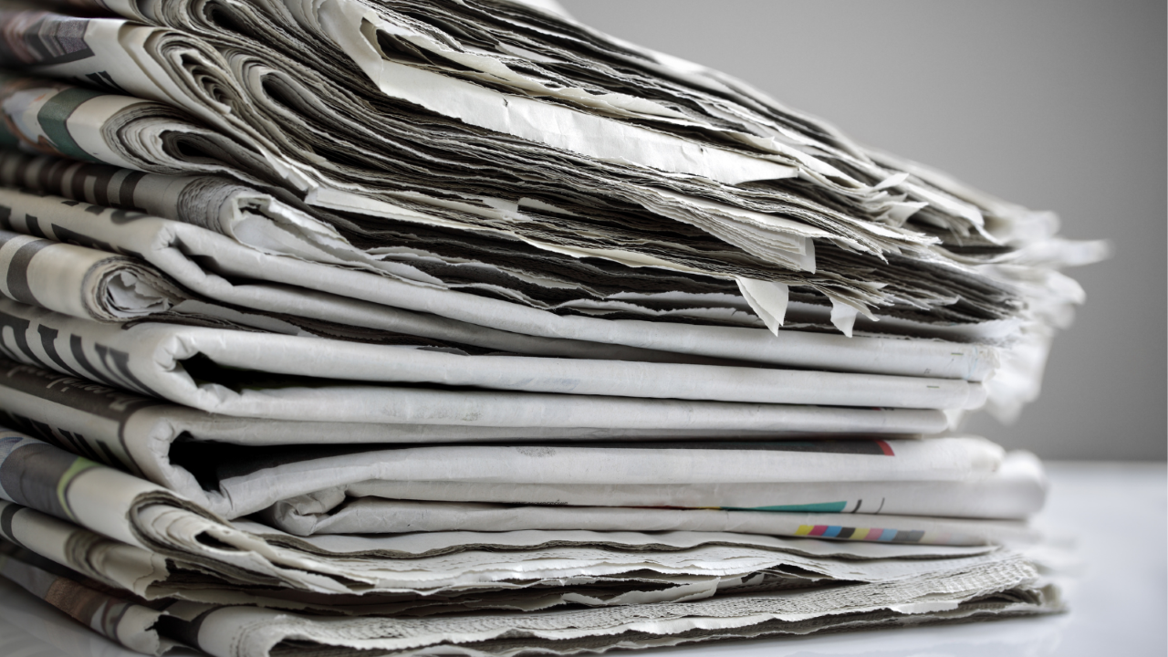 Newspapers stacked on a table.