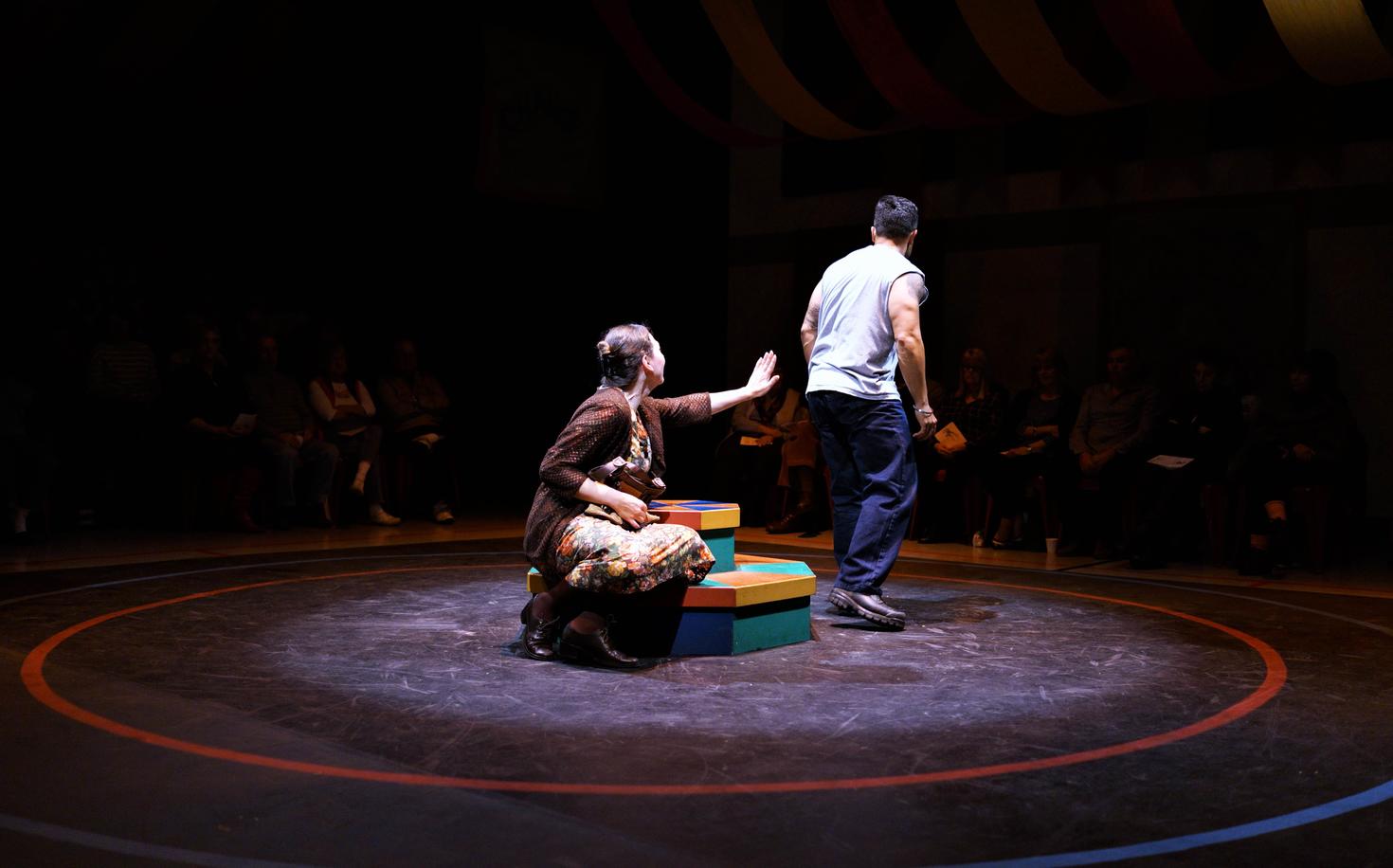 A woman and a man acting out a scene in front of an audience