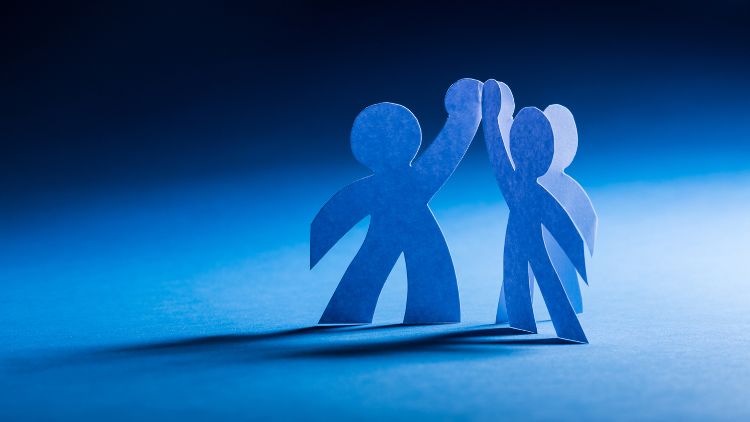 Photo of paper cutouts in the shape of people high-fiving.