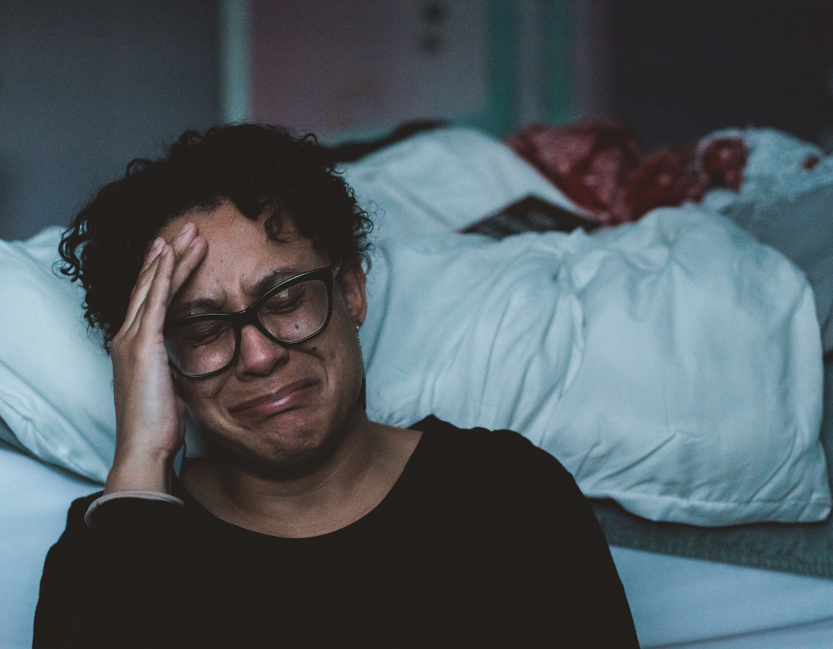 Middle-aged Black woman at foot of bed crying