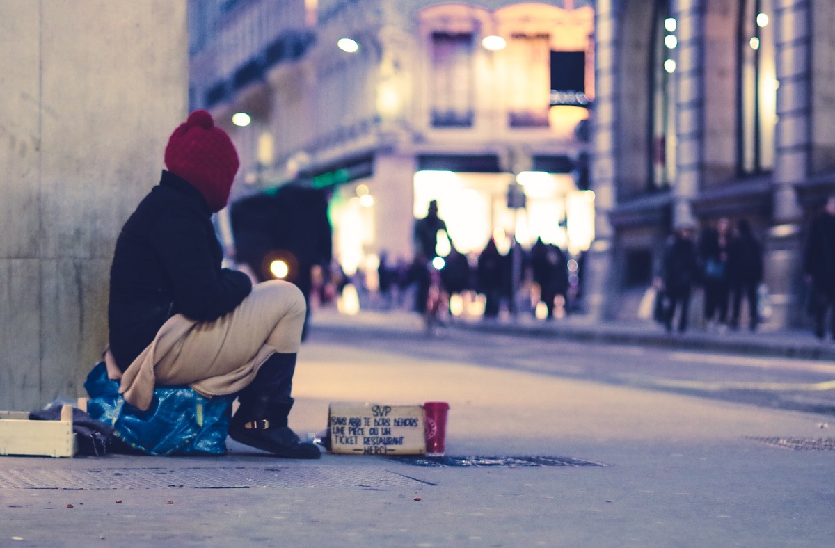 Person on street with sign pleading for money