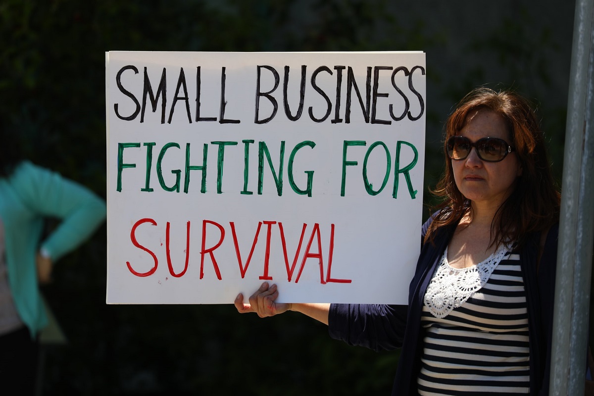 Woman holding sign that reads 'Small business fighting for survival'