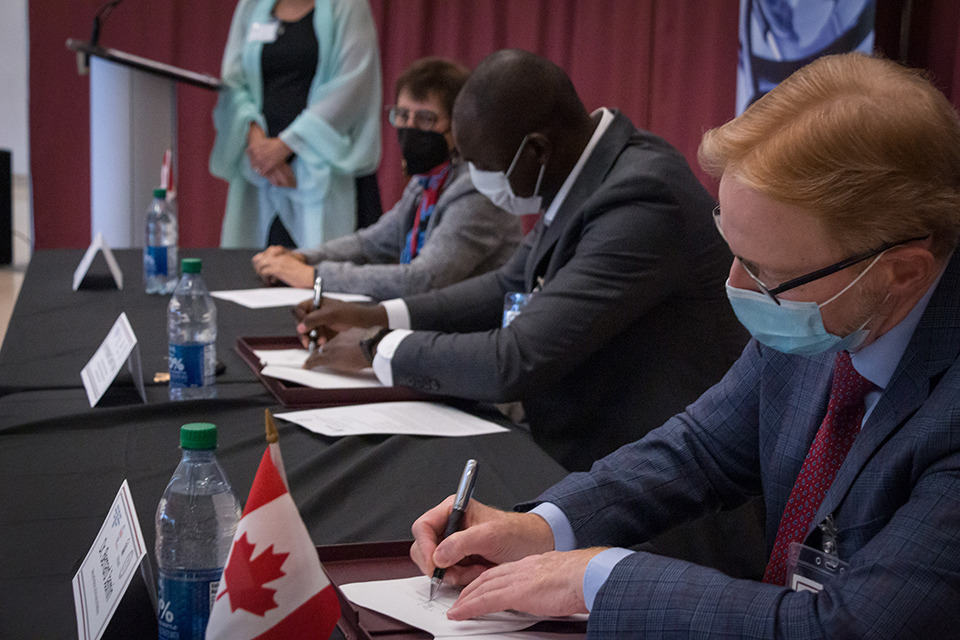 Trois dirigeants signant des documents à une table.