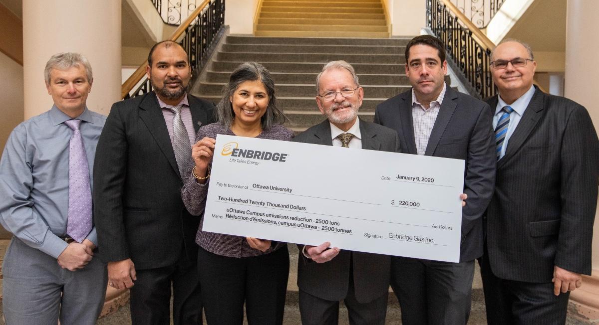 Un groupe de dignitaires tient le chèque géant remis par Enbridge Gas à l'Université d'Ottawa, sur lequel il est inscrit la somme de 220 000$