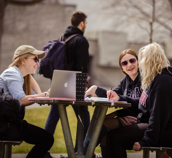 Étudiants étudiant à une table de pique-nique à l'extérieur.