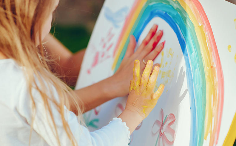 childs hand paints a rainbow