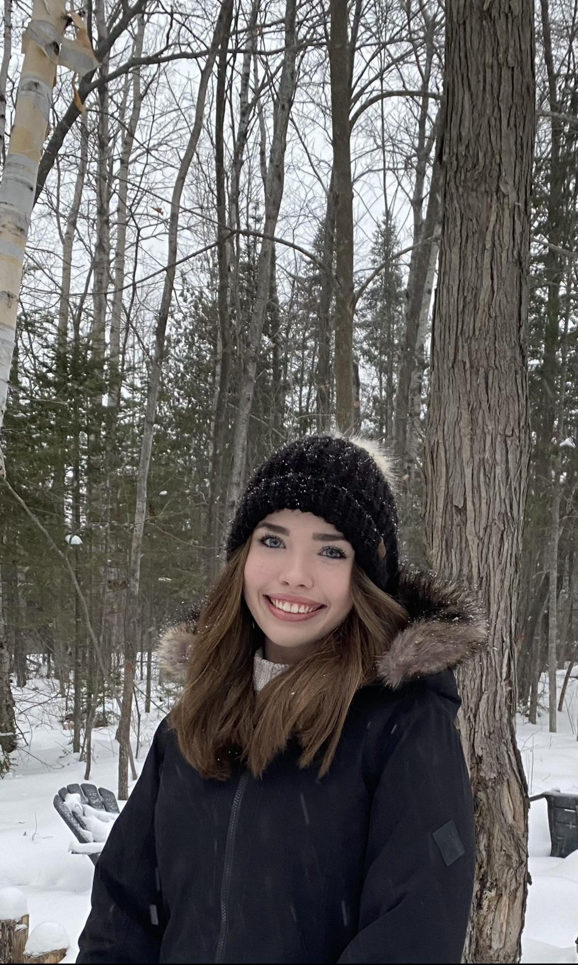 Addison Bond portrait image smiling in a forest during winter