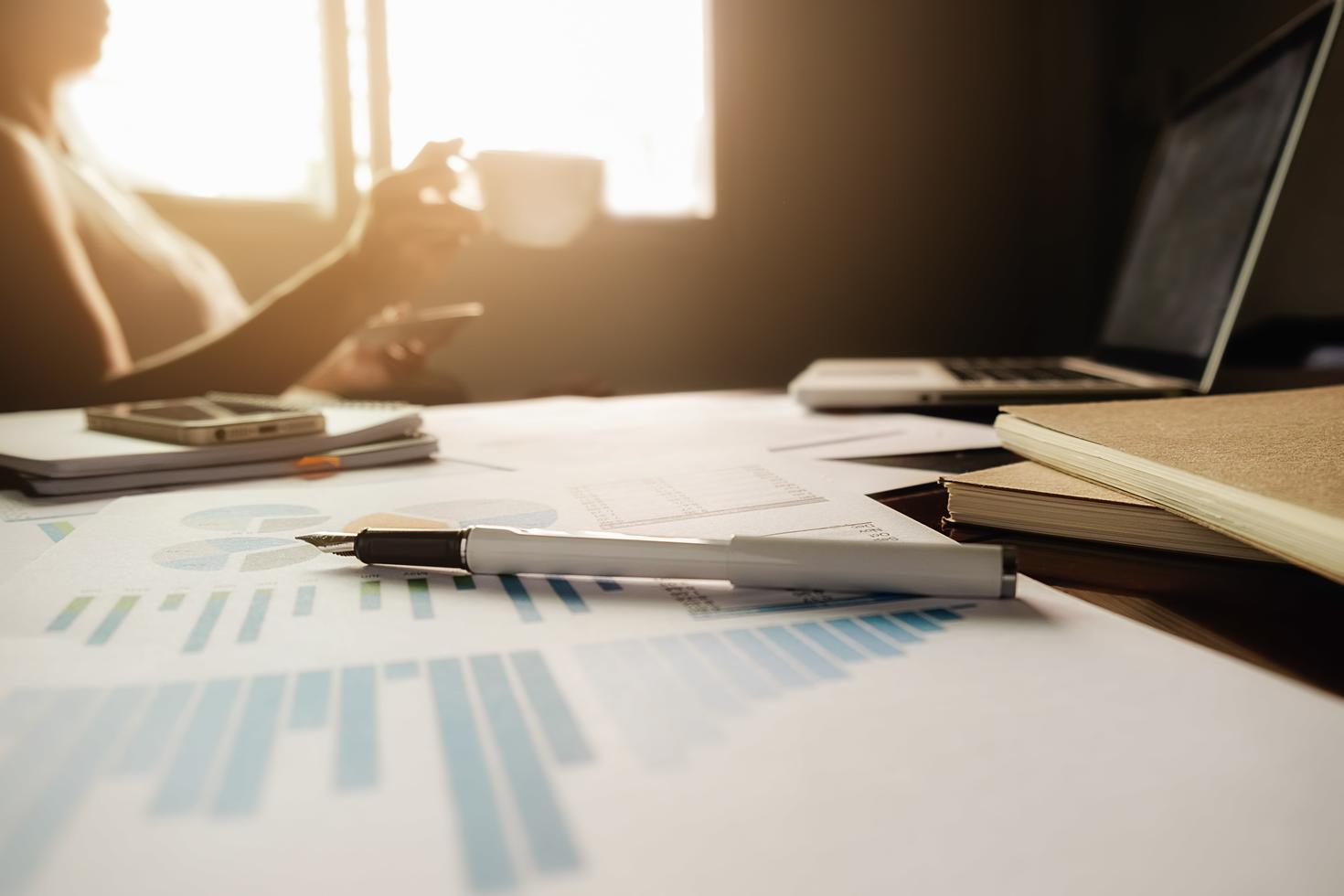 table de bureau avec stylo, tableau d'analyse, ordinateur et cahiers