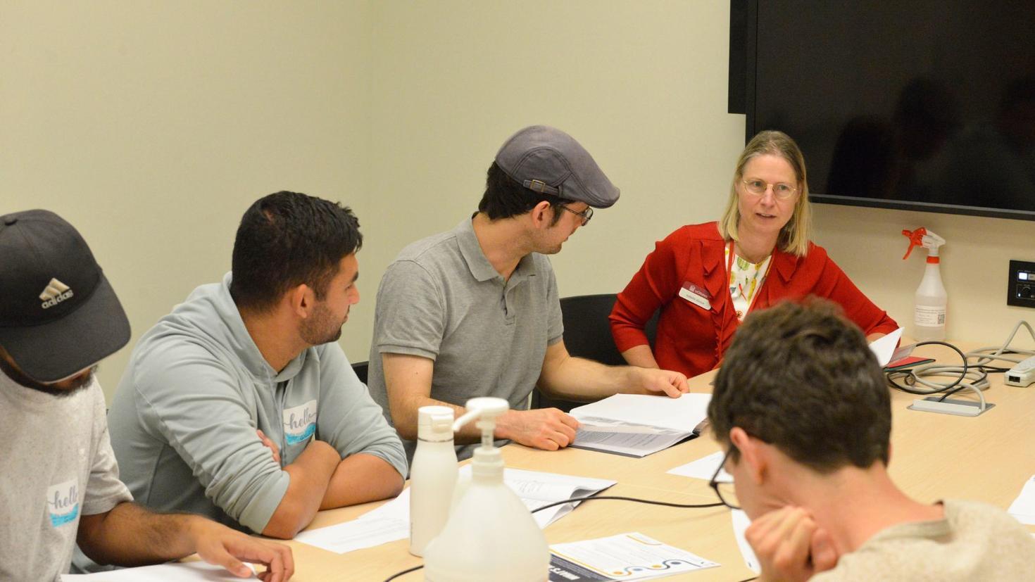 Group of students working at table with professor