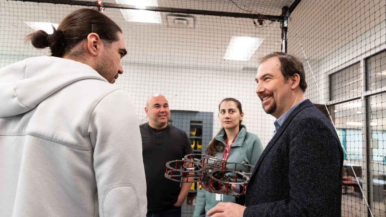 Professor Burak Kantarci speaking with students and holding a drone