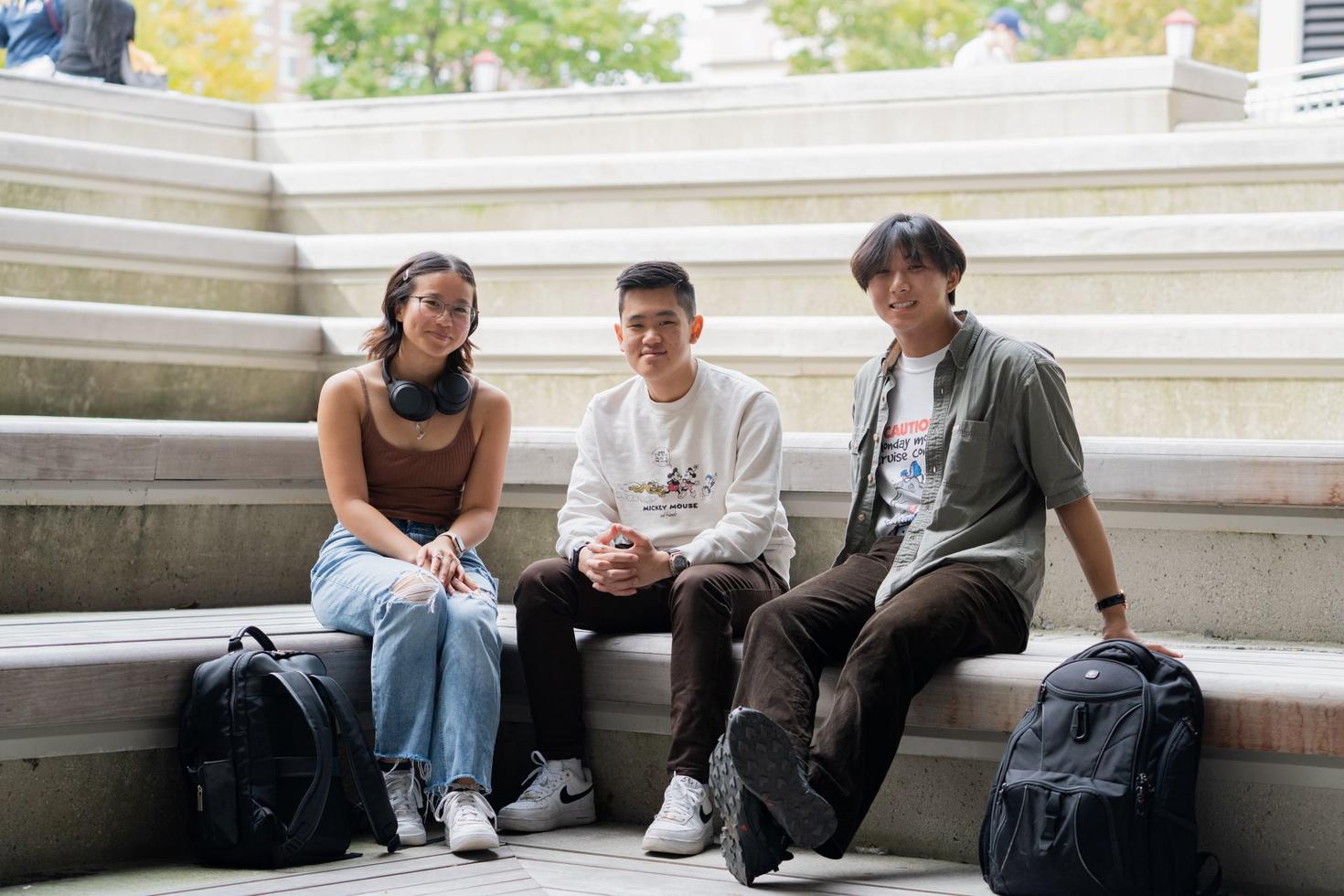 Trois étudiants assis sur des marches en béton sur le campus de l'université d'Ottawa.
