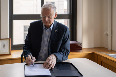 Le recteur Jacques Fremont signe la charte de Scarborough à son bureau.