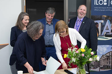 Catherine Buchanan signant un document entourée de 4 autres personnes.