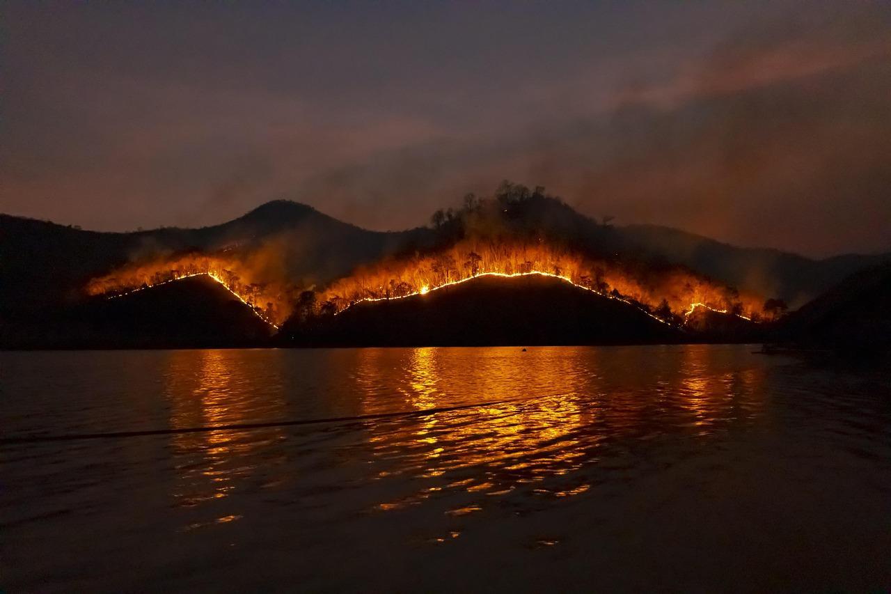 Wildfire breaking out on hill across a lake.