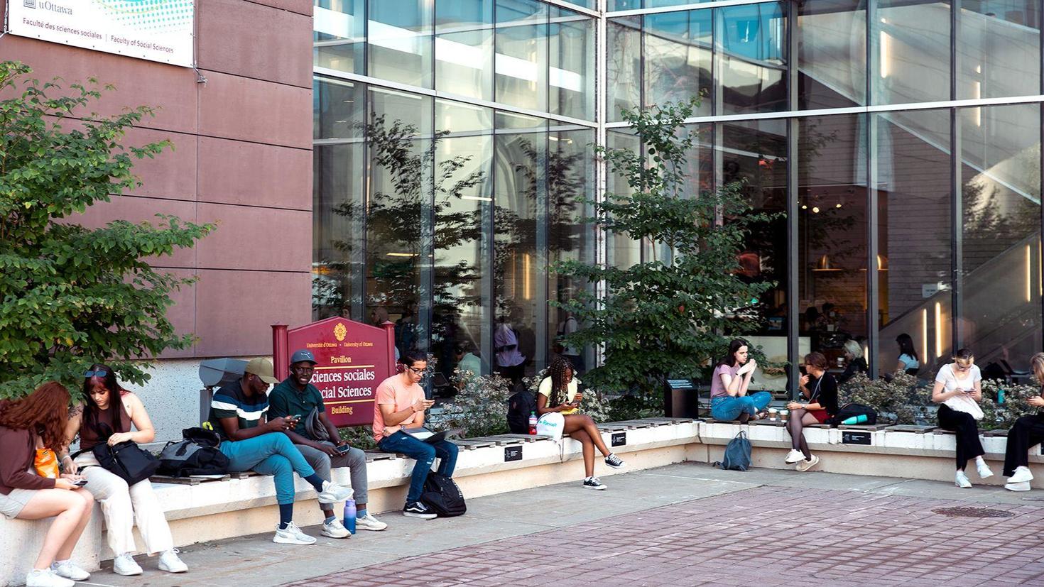 Des étudiantes et étudiants devant le bâtiment de la Faculté des sciences sociales.