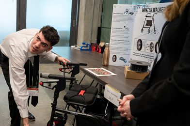 Student presenting a red and black wheel from the winter walker prototype.