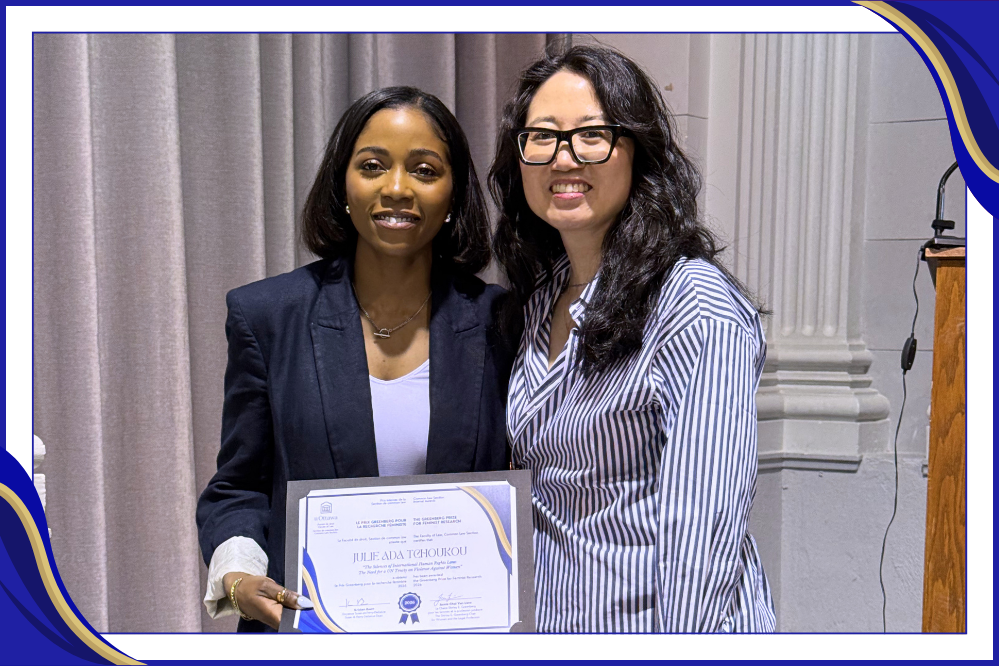 Two women stand, shoulder-to-shoulder and smiling. The woman on the left is holding a certificate. 