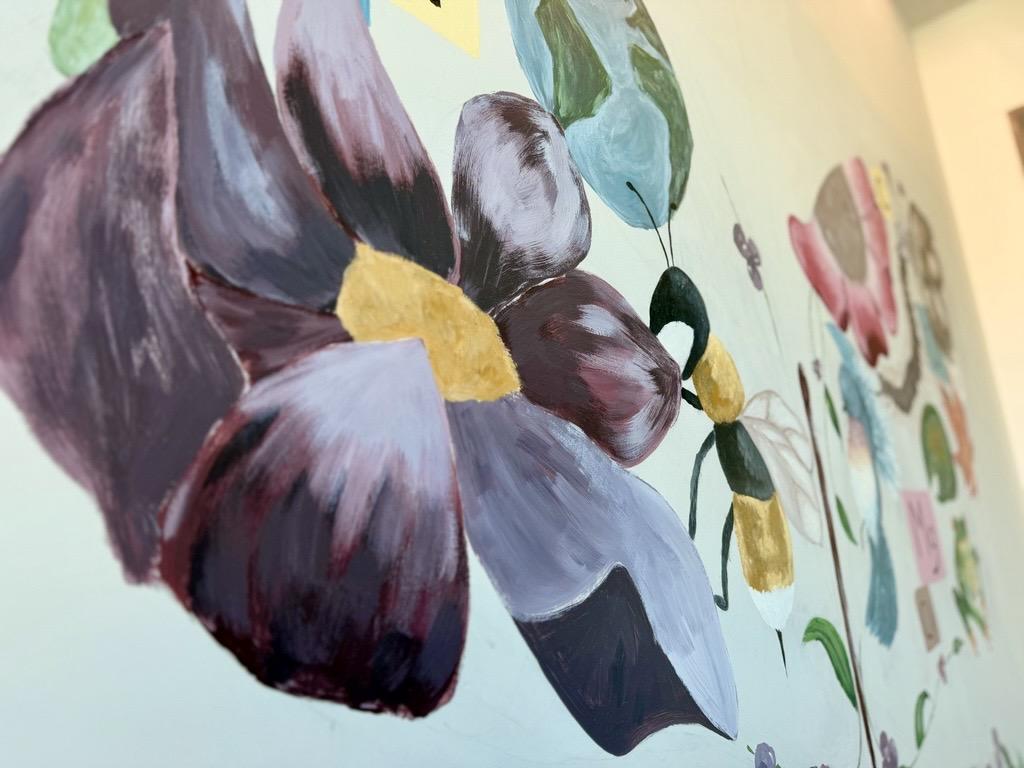 Gros plan sur une peinture murale représentant une fleur et une abeille.