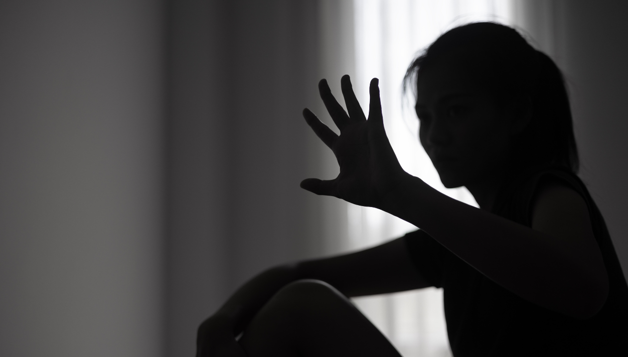 Femme dans un pièce sombre la main levé