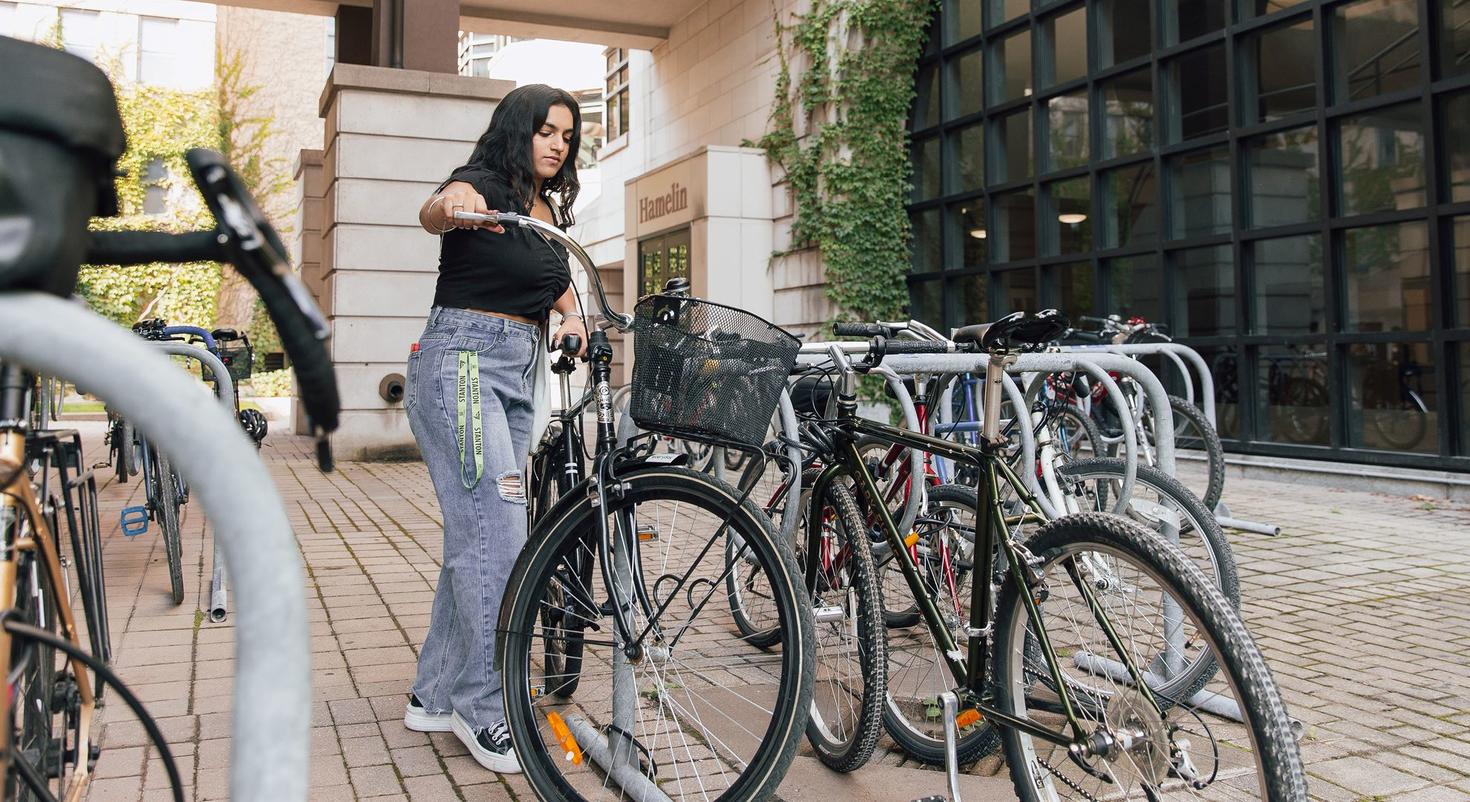 Une étudiante prend son vélo dans un porte-vélos sur le campus de l'Université d'Ottawa.