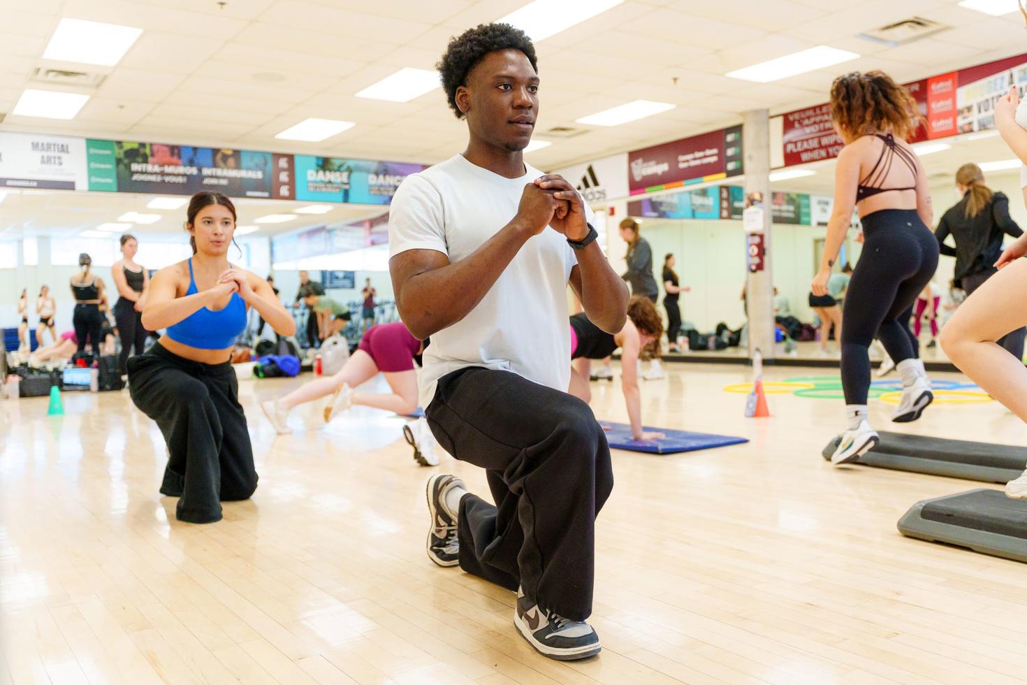 Des étudiantes et étudiants d'un cours de fitness en train de faire des fentes.