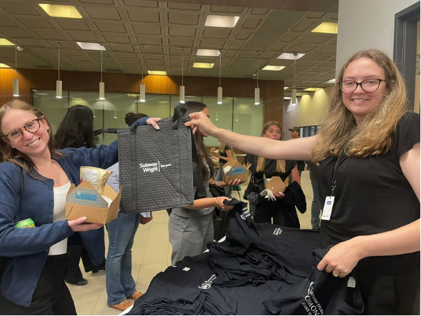 Female student group member handing out a bag to another female student
