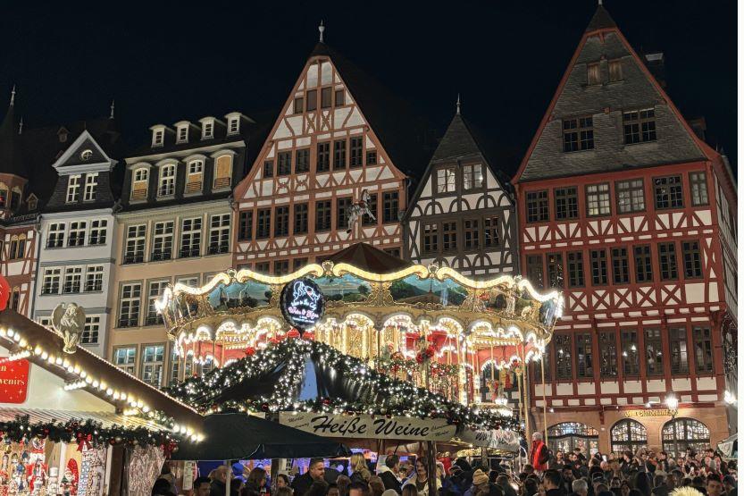 A merry-go-round lit up at night surrounded by houses in a town square in Germany.