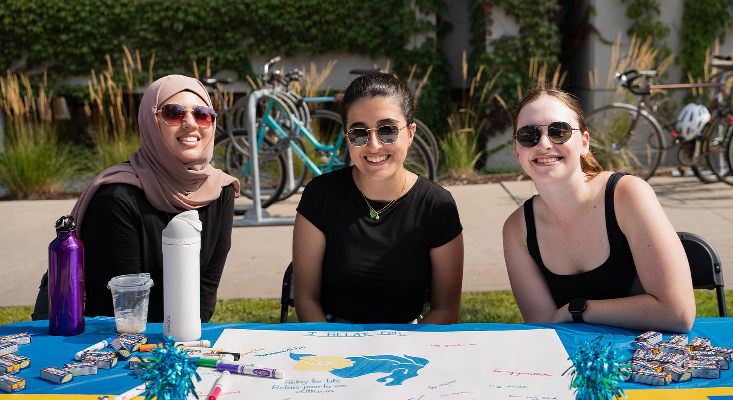 Three members of a student club at a table at the 2025 Club Fair.