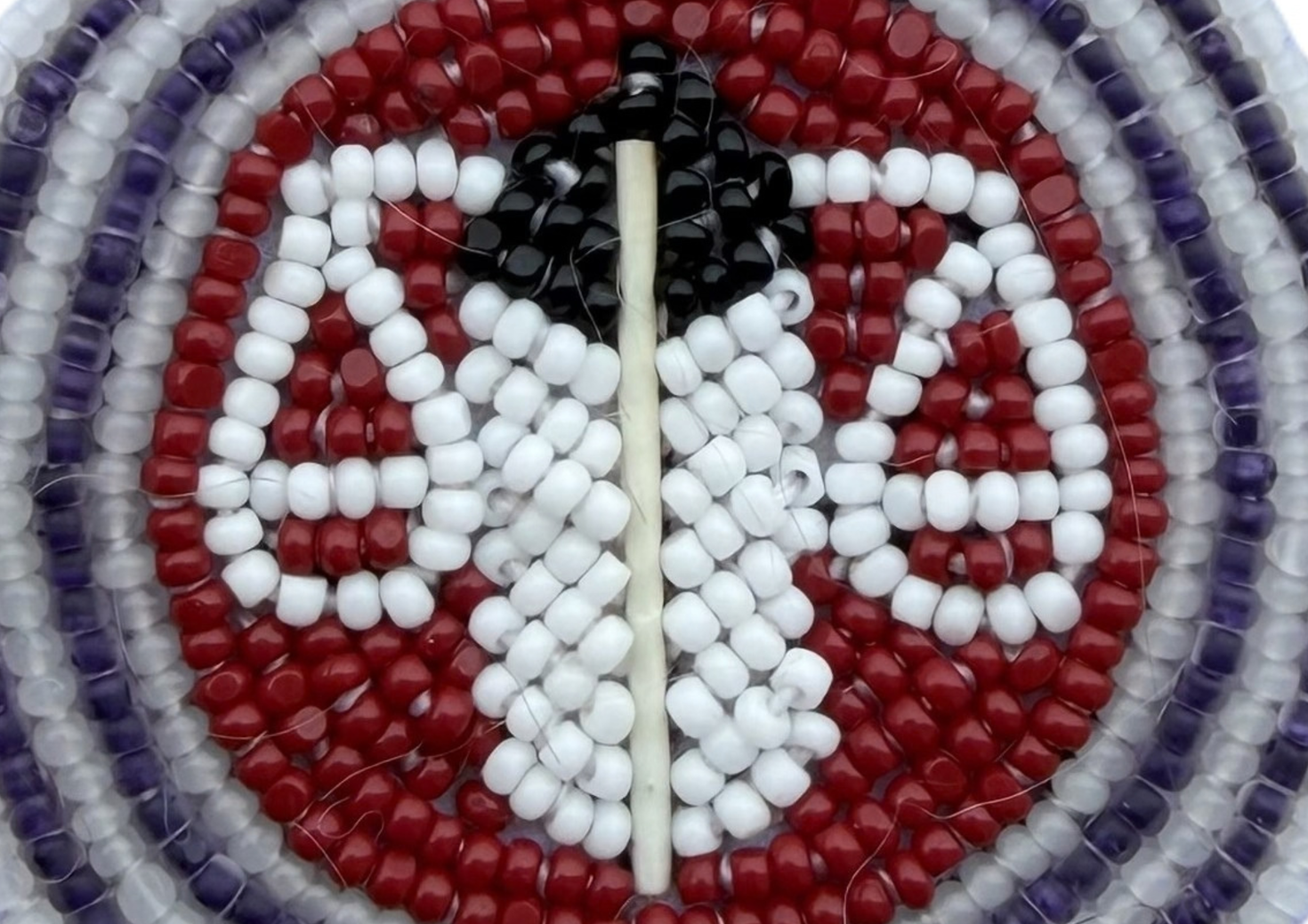 Beadwork representing white scales on a dark red background