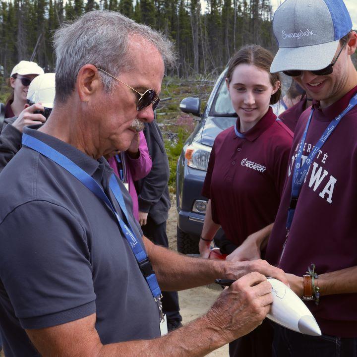 L'astronaute canadien Chris Hadfield signe le cône de nez de la fusée « Perigee-Gee » sous le regard émerveillé de l'étudiant Nicholas Kuzyshyn.