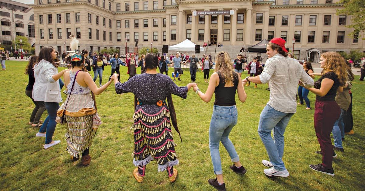 Des étudiants autochtones se tiennent la main avec d'autres étudiants de l'Université d'Ottawa dans un grand cercle sur la pelouse de Tabaret.