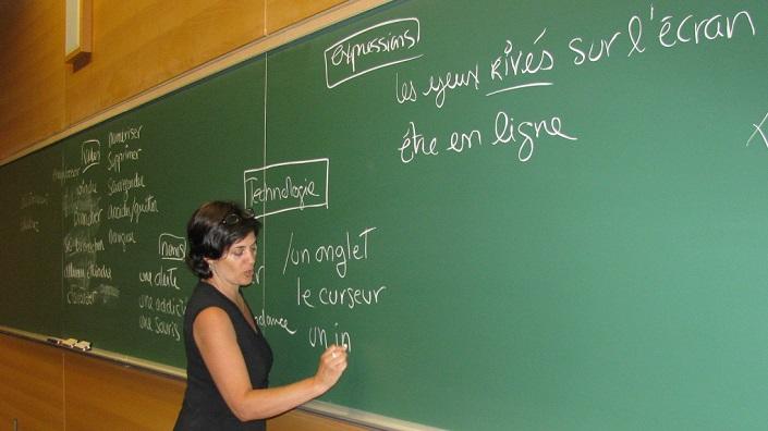 ILOB teacher at a blackboard teaching vocabulary related to new technologies.