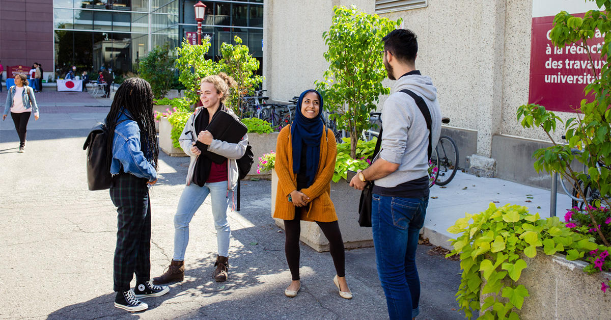 Des étudiantes et étudiants discutent à l'extérieur sur le campus