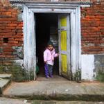 A child wearing a pink top and jeans opening the front door