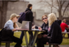 Group of students sitting outside at picnic tables.