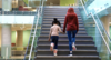 Two people walking up modern staircase holding hands.