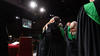 Two graduating students on stage hugging in celebration of graduating.