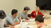 A group of students working at a table with their professor