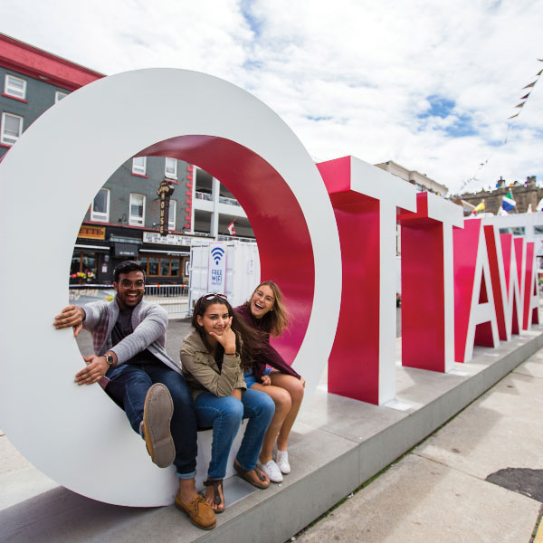 Students sitting in a Ottawa sign